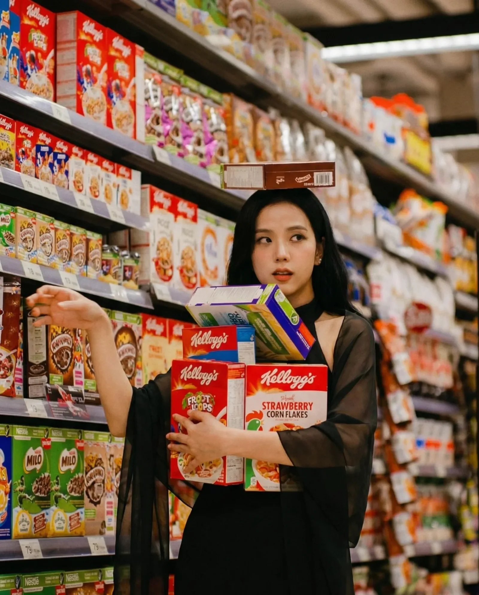Donna in abito nero in un supermercato mentre prende diverse scatole di cereali dagli scaffali del reparto alimentari.
