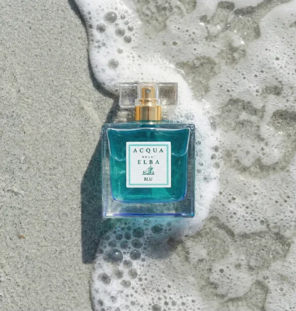 Flacone di profumo su sabbia bagnata con schiuma del mare, immagine prodotto ambientata in spiaggia