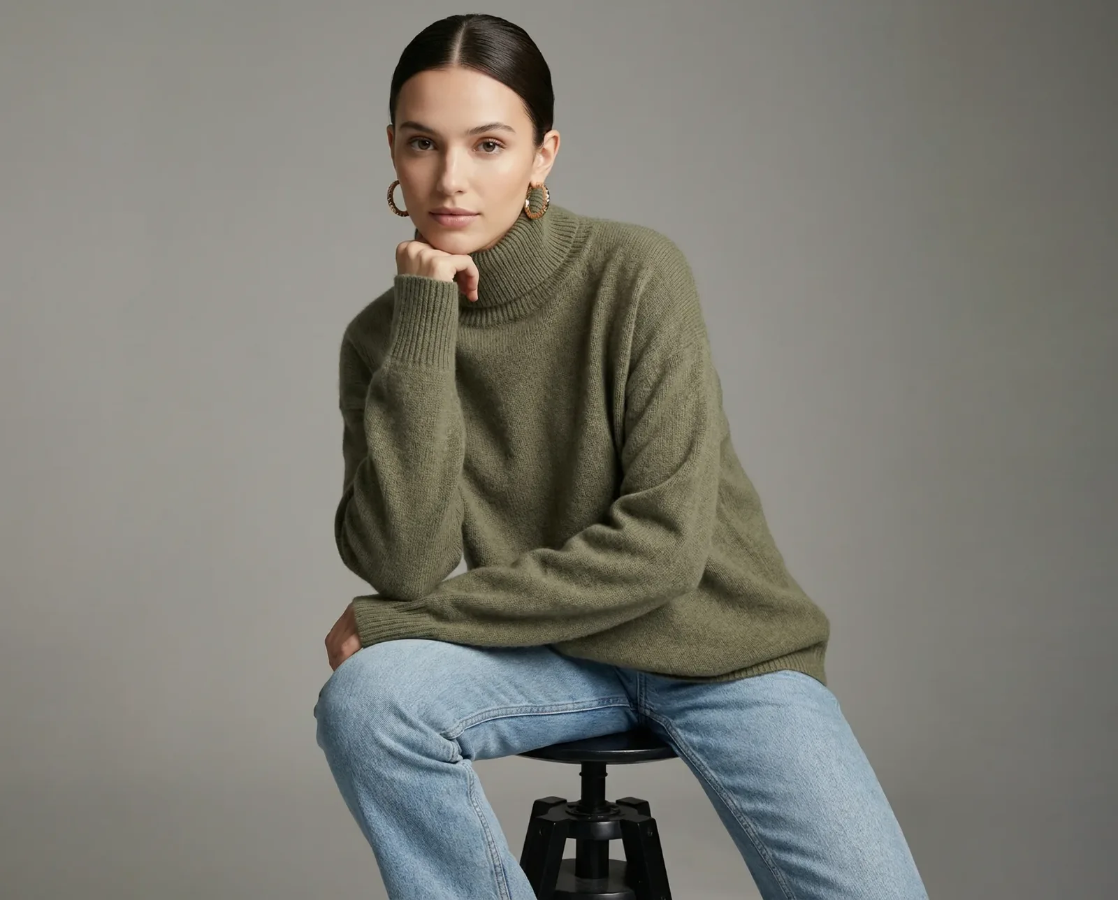 Immagine e-commerce con modella in maglione verde e jeans su sfondo neutro