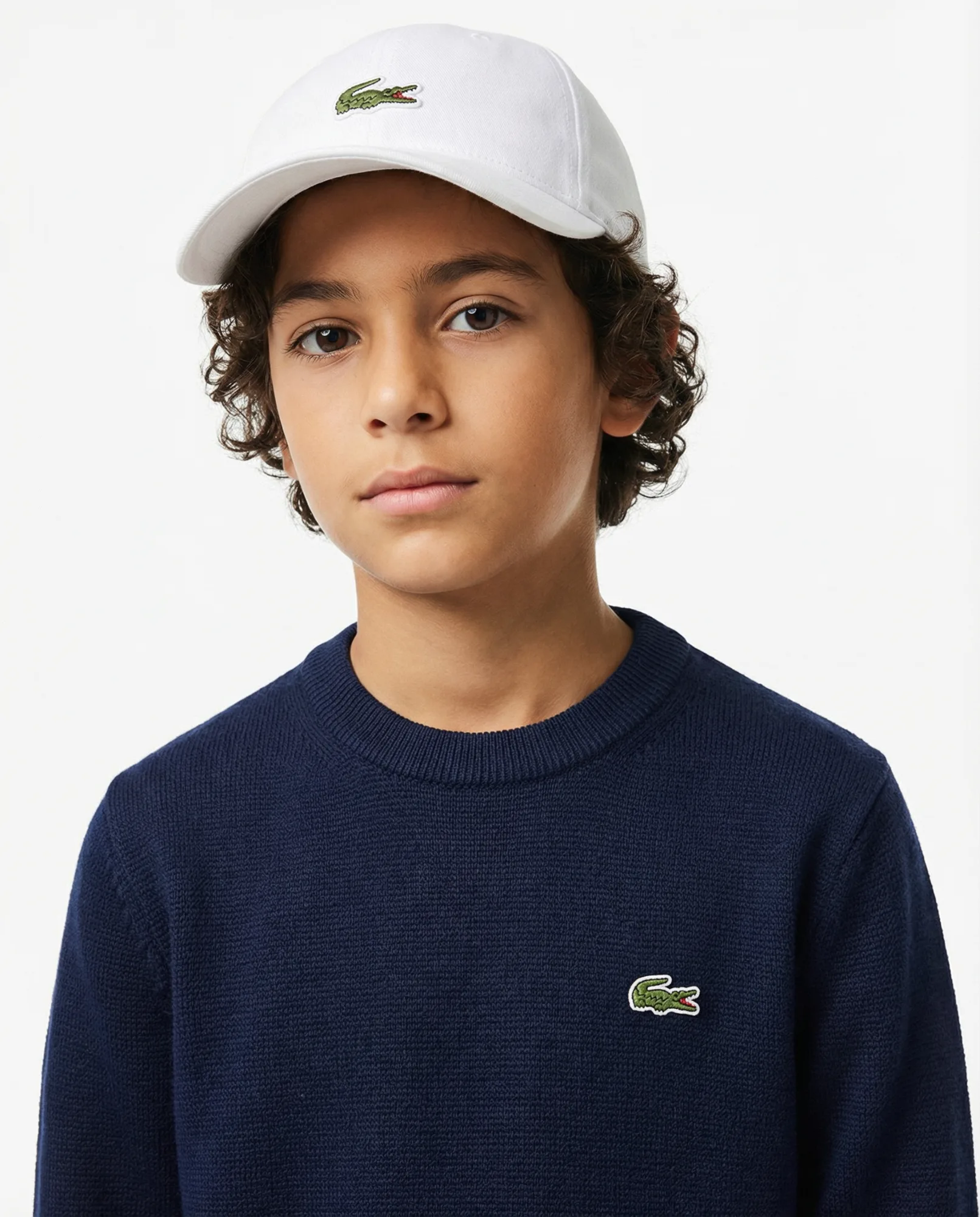 Immagine e-commerce con giovane modello in maglione blu e cappellino su sfondo neutro