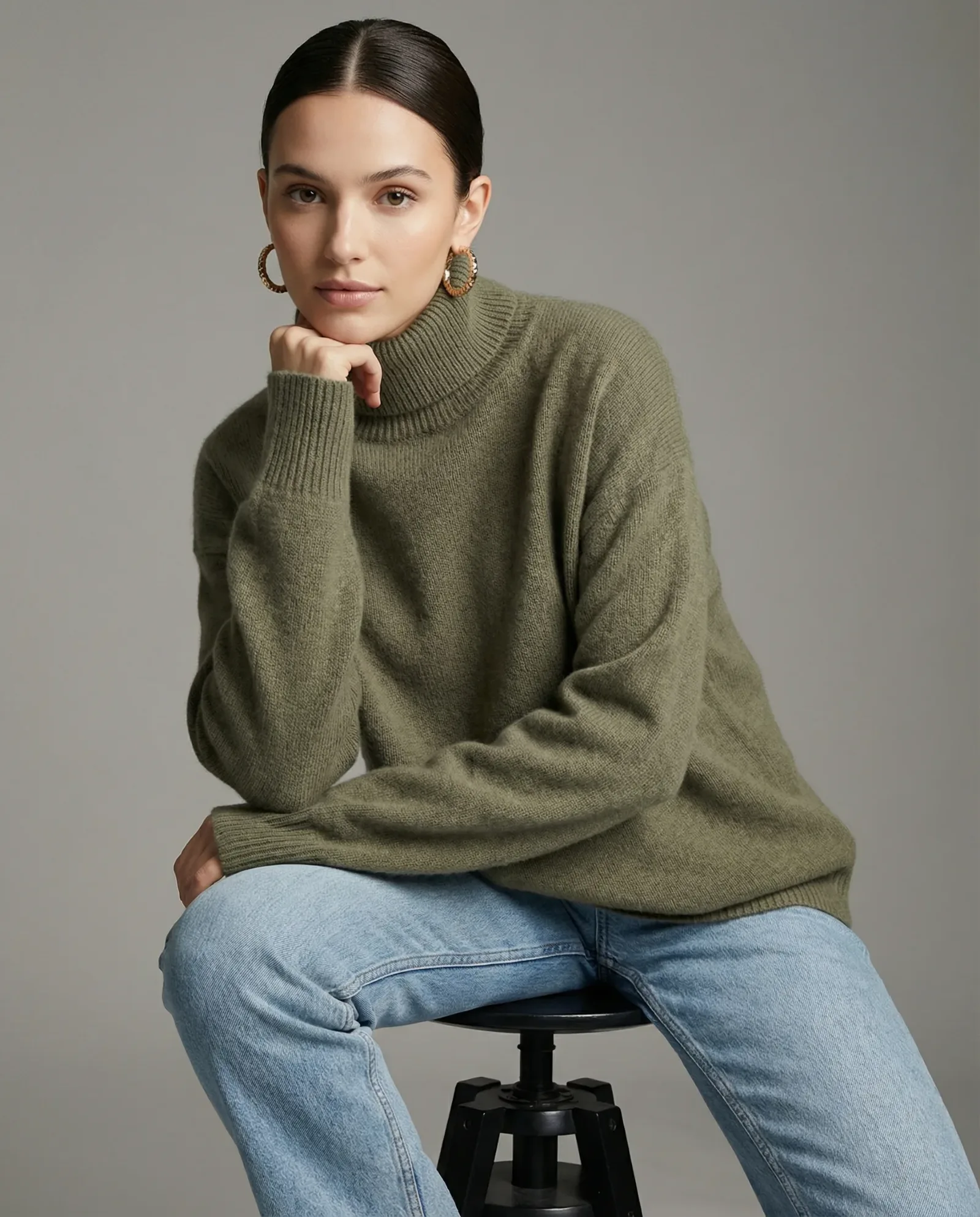 Immagine e-commerce con modella in maglione verde e jeans su sfondo neutro