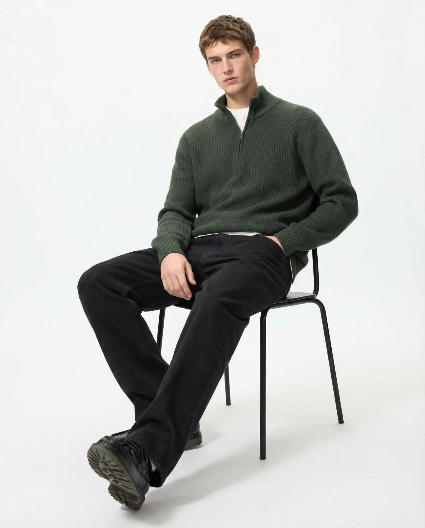 Immagine e-commerce moda con lo stesso maglione verde indossato da modello seduto su sfondo neutro