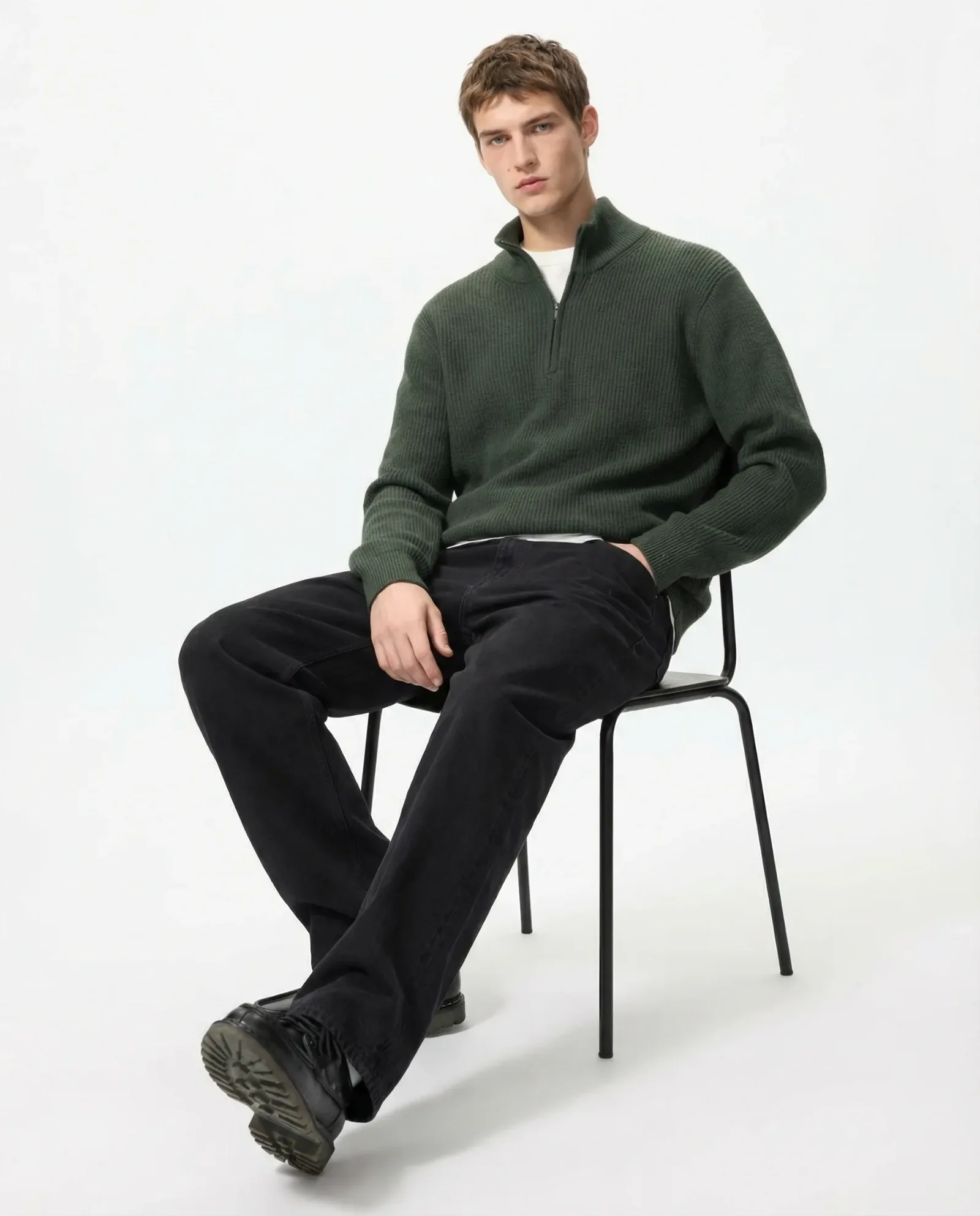 Immagine e-commerce moda con lo stesso maglione verde indossato da modello seduto su sfondo neutro