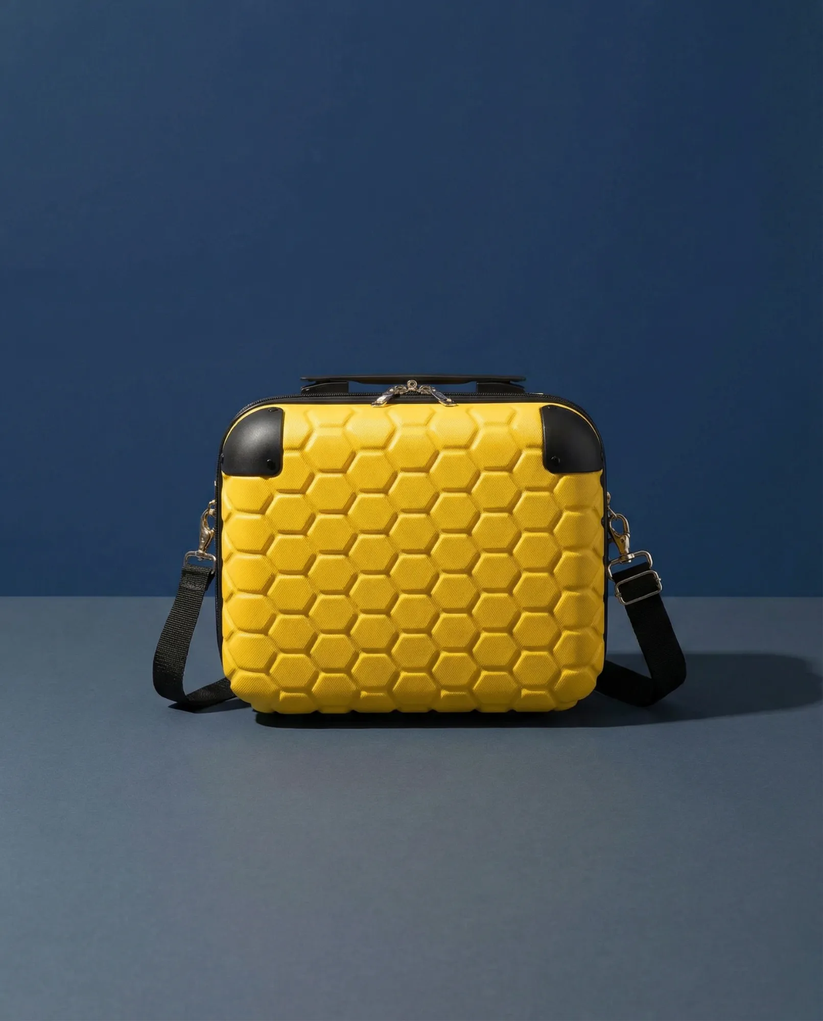 Borsa rigida gialla con texture a nido d'ape fotografata su fondo blu scuro, immagine prodotto accessori dal design moderno