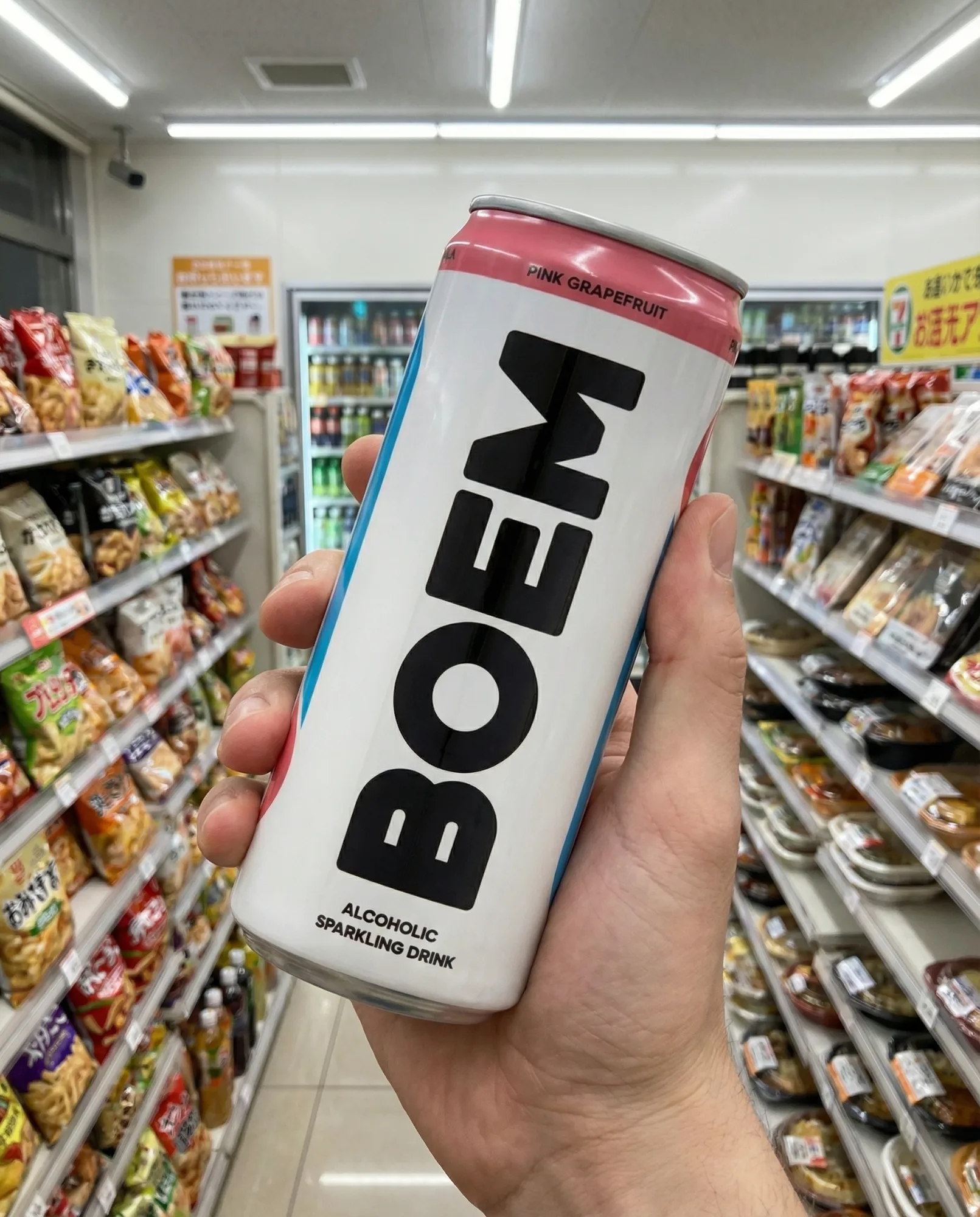 Mano che tiene una lattina di bevanda tra gli scaffali di un supermercato, con prodotti alimentari sullo sfondo.