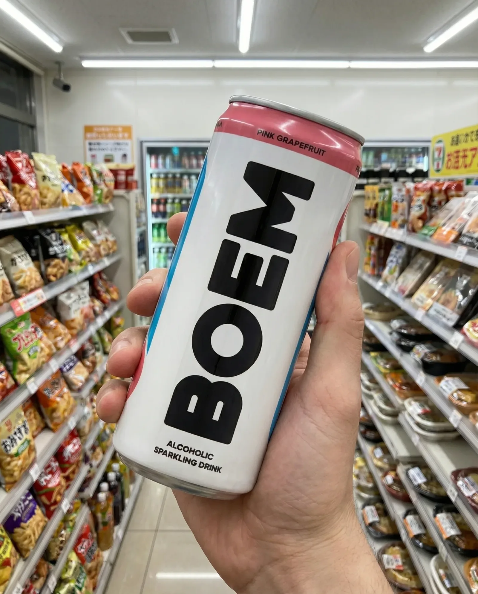 Mano che tiene una lattina di bevanda tra gli scaffali di un supermercato, con prodotti alimentari sullo sfondo.