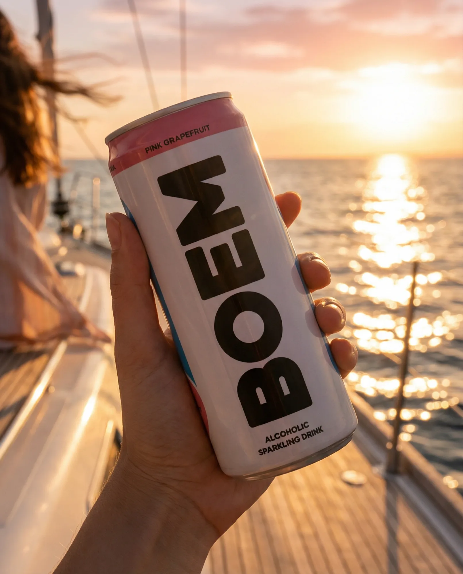 Lattina di bevanda energetica tenuta in mano al tramonto su una barca a vela, lifestyle estivo