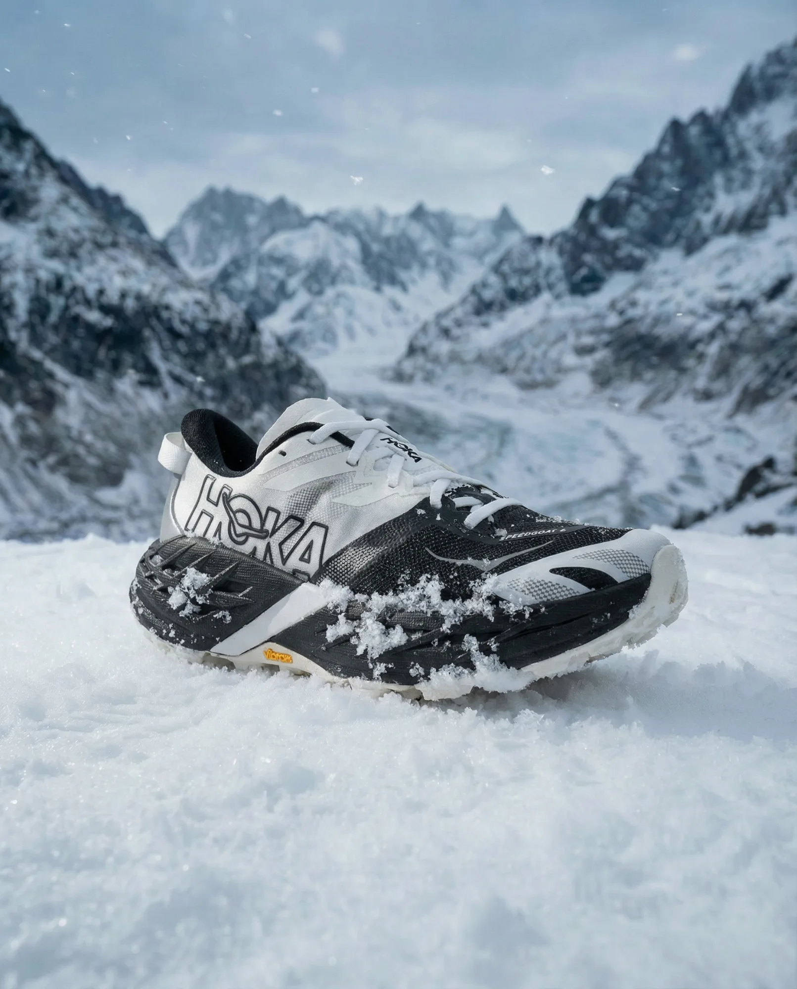 Scarpa da trail running su neve fresca con montagne innevate sullo sfondo, fotografia prodotto sportiva in ambiente alpino